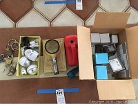 Wide shot of all items in lot including boxes of X10 modules, various flashlights, magnifying glass flashlight, locks, and small accessories.