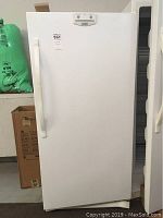 Front view of the white Kenmore upright freezer showing door and handle, closed.