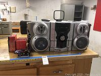 Sharp stereo system with 5 CD changer, silver finish, alongside stacks of blank cassette tapes on a wooden table.