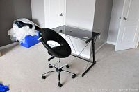Desk and chair set shown in a carpeted room, angle showing chair facing away from door, minor wear visible on chair upholstery.