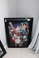 Framed portrait print of Harley Quinn holding a baseball bat in front of a colorful neon Suicide Squad logo