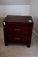 Front view of the closed wood side table with two drawers showing metal handles and dark brown finish.