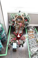 Front view of wooden lantern stand, Christmas wreath behind, red berry candle centerpiece in front, and stack of golf balls to side