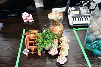 Wide shot of entire lot showing vase, wine holder with elephants, fairy figurines, artificial plant, and small boxes.