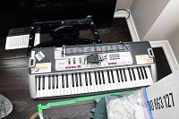 Front view of Casio keyboard showing 61 keys, control panel and part of the power cord