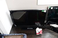 Insignia 38 inch TV on the floor with remote on its stand and power cord on side.