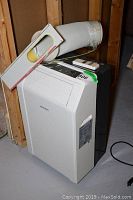 White front and top view of Brada portable air conditioner with vent hose and remote on top