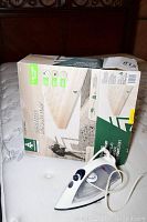 Photo of small iron placed on mattress surface, box is visible in the background.