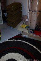 5x7 feet rug with black, red, white concentric circle pattern shown with stacked olive couch cushions and rug remnants around it.