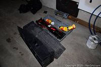 Photo showing two black plastic car ramps, two scissor type car jacks in gray plastic carrying cases, and three yellow and orange cans of Armor All car care spray on a concrete floor.