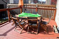 Wooden slatted patio table with six chairs and green umbrella folded on top