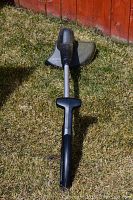 Black and Decker electric weed trimmer lying on grass showing full length and handle