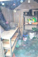 View of garden tools and supplies neatly stored inside a plastic shed, including rakes, shovels, gloves, rubber boots, flower pots, chemicals, grill, and shelving units.