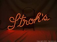 Frontal view of lit neon sign with 'Stroh's' cursive writing in orange-red color