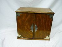 Front view of closed oak pipe box showing double doors and nickel hardware