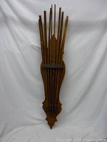 Front view of the folded antique wooden laundry drying rack showing multiple wooden poles tightly together with an ornate shaped wooden base.