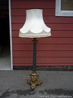 Full height view of lamp against exterior wall showing base, shaft and shade
