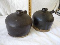 Front view of both antique Chinese soy sauce ceramic jugs side by side with ruler for height reference