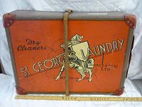 Front view of vintage orange laundry box with St. George's Laundry branding and a leather strap closure.