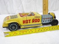 Side view of the yellow tin litho hot rod car showing 'HOT ROD' lettering and size reference with measuring tapes.