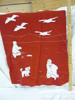 Front view of red felt art panel with white appliqué Arctic figures and birds alongside a wooden ruler for scale
