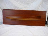 Front view of wooden wall shelf with ship hull shape on rectangular backboard on cloth background