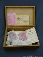 Wooden box with various vintage WWII-era documents including passes, certificates, and pamphlets
