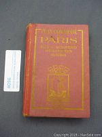 Front cover of the vintage Paris guide book titled 'Plan Commode Paris' with gold lettering and emblem on reddish cover.