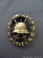 Front view of the WWI German Wound Badge showing helmet and swords within laurel wreath.
