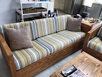 Front view of one couch with striped cushions and beige pillows showing solid pine wood framing and cushion details.