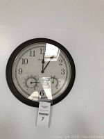 Front view of Acurite round wall clock showing time and dual meter dials for temperature and humidity.