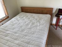 Straight view of bed frame with white mattress and bedspread, showing headboard and side rails.