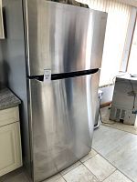 Full front view of closed refrigerator showing stainless steel finish and freezer on top