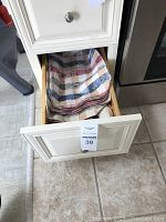 Open kitchen drawer containing multiple folded kitchen towels and linens with various striped and plaid patterns.