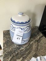 Photo of a white porcelain cookie jar with a blue swirl pattern and lid on a granite counter.