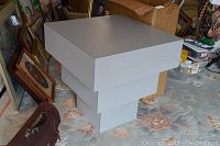 Photo of modern square coffee table with stepped base design from an angle showing white laminate finish.