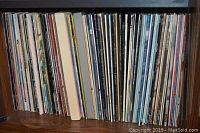 Shelf full of approximately 80 vinyl record albums showing varied cover spines, indicating multiple artists and labels