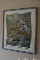 Full view of framed print hung on wall showing garden scene with woman and water lilies.