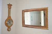 Photo of a gold-framed mirror and German barometer on wall