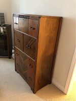 Side angle showing full height and depth of wooden dresser with decorative drawer fronts.