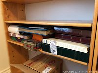 Shelf view showing multiple albums, binders, boxes, tin