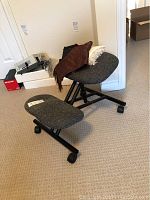 Photo showing gray fabric kneeling chair with black metal frame and casters, and several scarves draped over the chair.