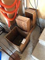 Six vintage wooden storage boxes in various sizes and shapes grouped on floor near wall and pipes