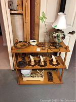 Wooden shelf with lamp, scale, weights, decorative plate, bowl, ceramic duck shakers, and glass bottle with butterfly decoration shown front view.