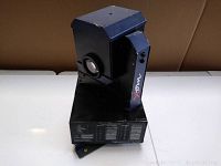 Side angle of the vintage Mac X DJ light showing the lens and blue accents on top and side.