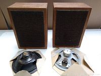Pair of vintage wooden speakers with black fabric grills and two separate speaker drivers in cardboard and tape.