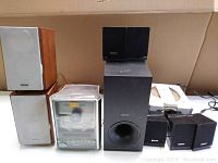 Photo of the stereo lot showing wood-finished Sony speakers, black subwoofer, four small Sony satellite speakers, and a Sony tape player