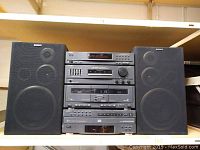 Full view of stacked Sony stereo system and two speakers on a shelf