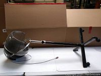 Photo showing the full vintage hair dryer unit with dome hood, chrome frame, adjustable stand with three-legged base on a white table.