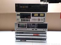 Front view of stacked audio components showing item facades including cassette decks, receivers, and DVD players